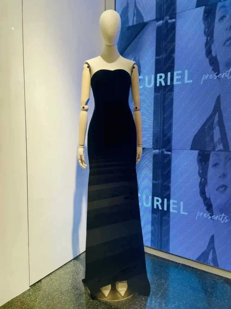 Vitrine CURIEL avec un mannequin femme gainé de lin beige, bras articulés en bois et socle rond en or brossé
