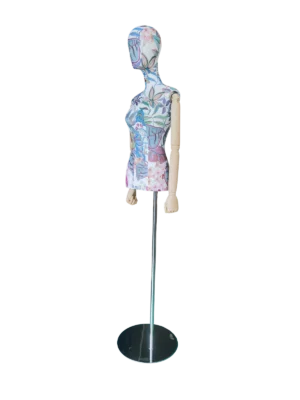 花柄の布地、抽象的な頭部、木製の腕、黒い丸い台座が特徴的な、XINTU の女性胴体マネキンの斜めビュー。.