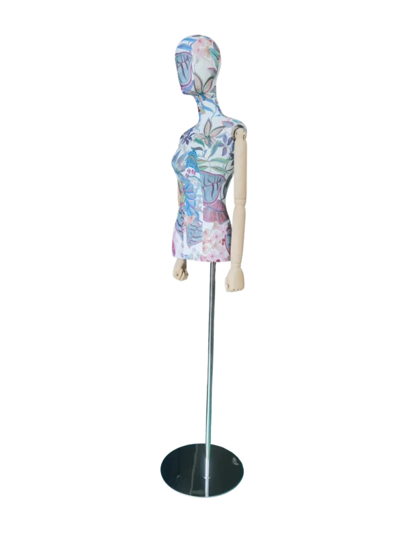 Angled view of a XINTU female torso mannequin, featuring a floral fabric pattern, abstract head, wooden arms, and a black round base.