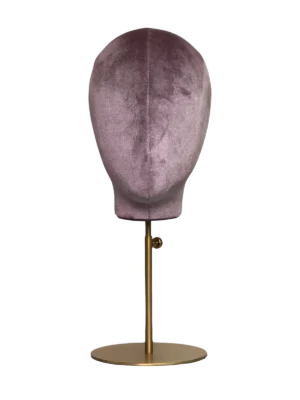 Vista frontal de una cabeza de maniquí abstracta XINTU, tapizada en terciopelo rosa púrpura, sobre un soporte redondo de metal dorado.