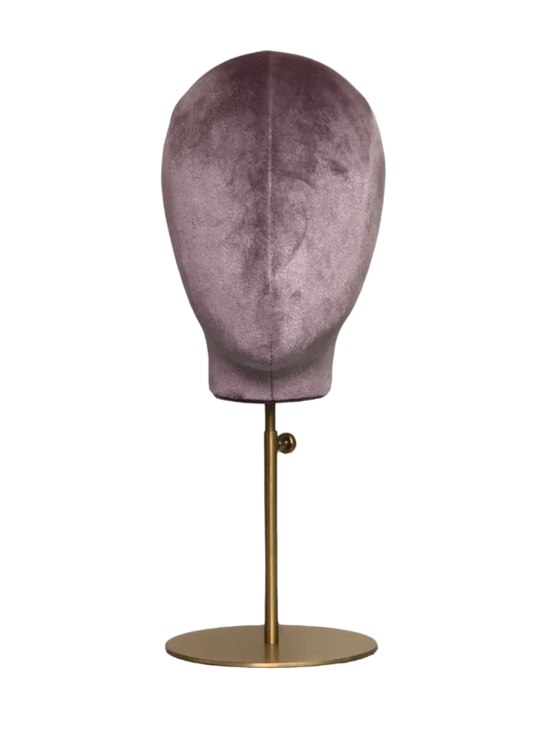 Vista frontale di una testa di manichino astratto XINTU, rivestita in velluto rosa-viola, su un supporto rotondo in metallo dorato.