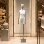 Fabric mannequin with wooden arms displaying a tailored dress in a luxury fashion retail setting