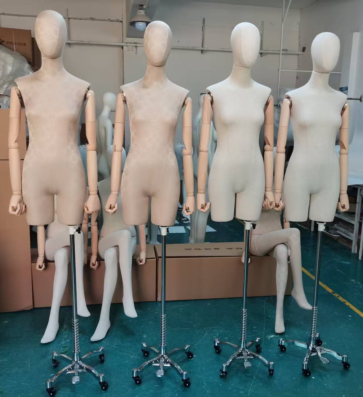 Four half-body fabric-covered female mannequins with articulated wooden arms on adjustable chrome tripod stands