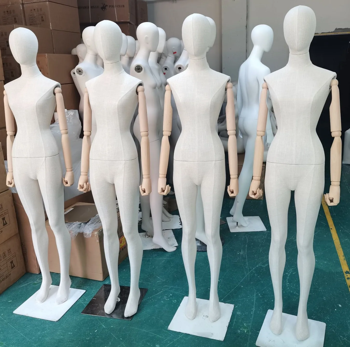 Four linen fabric-covered full-body female mannequins with articulated wooden arms at the XINTU factory in Shenzhen